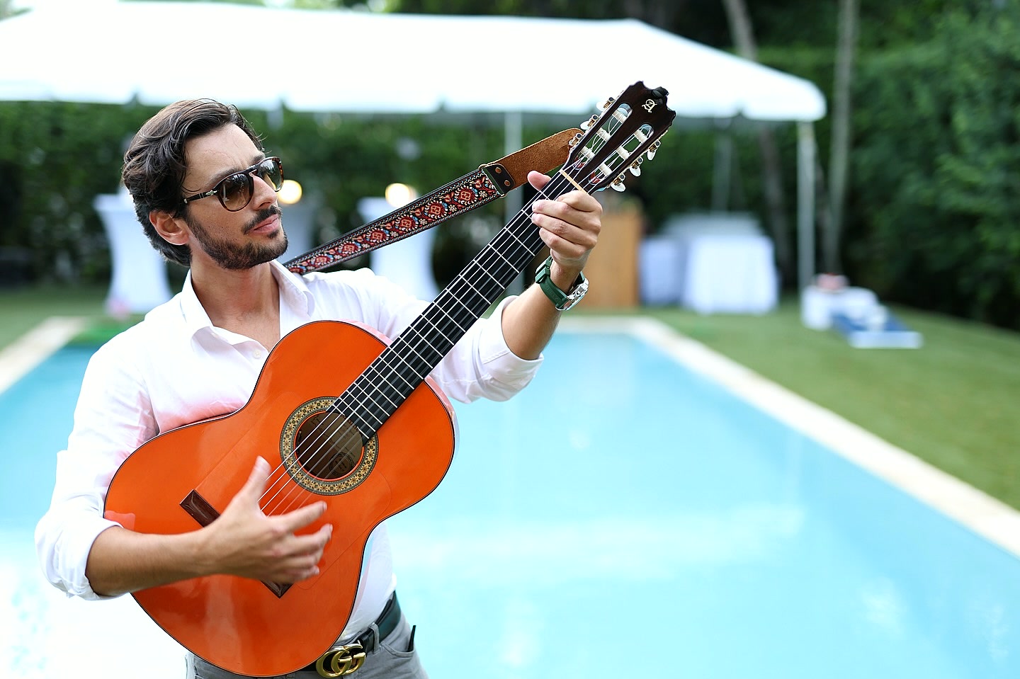 Sergio De Gouveia playing guitar at a poolside wedding ceremony