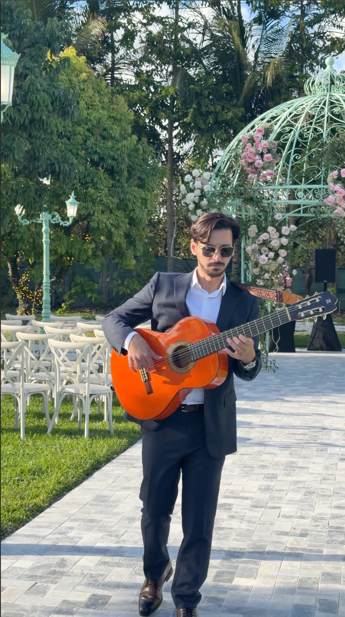 Sergio roaming with his guitar through a garden wedding